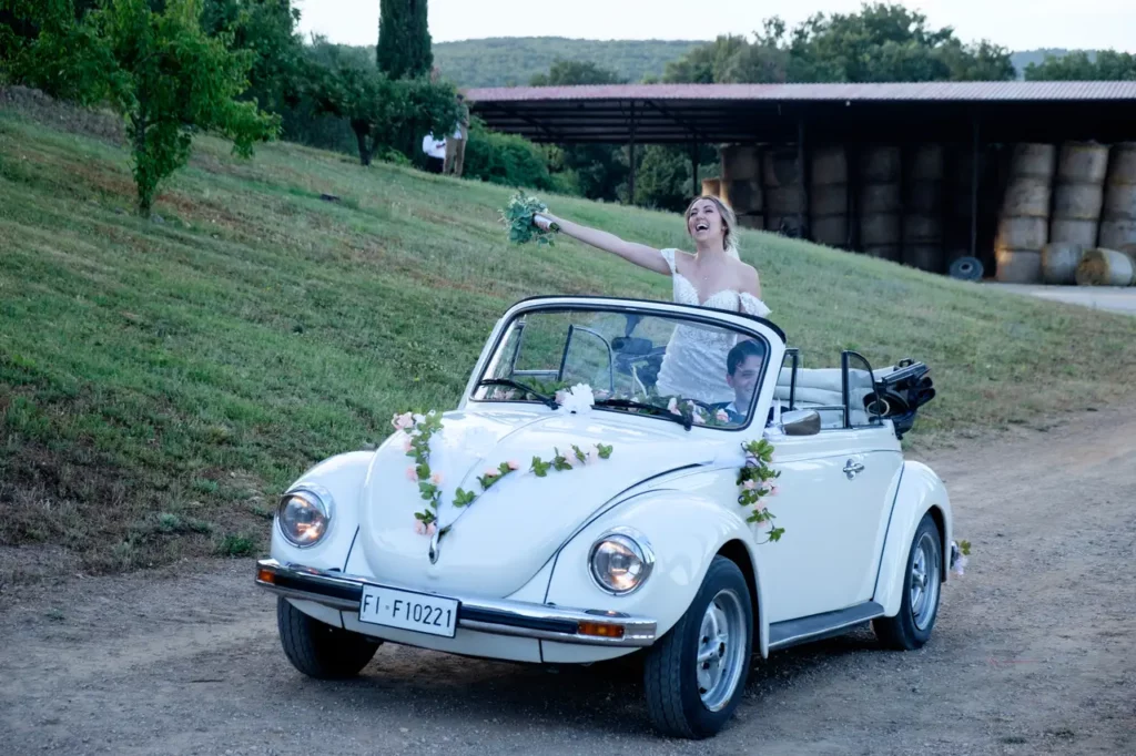 The bride and groom, in a white Beetle, arrive at the reception.